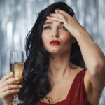 シャンパングラスを持ちながら頭を抱える女性