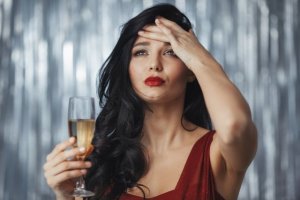 シャンパングラスを持ちながら頭を抱える女性