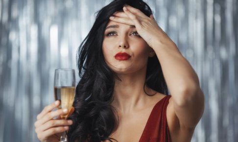シャンパングラスを持ちながら頭を抱える女性